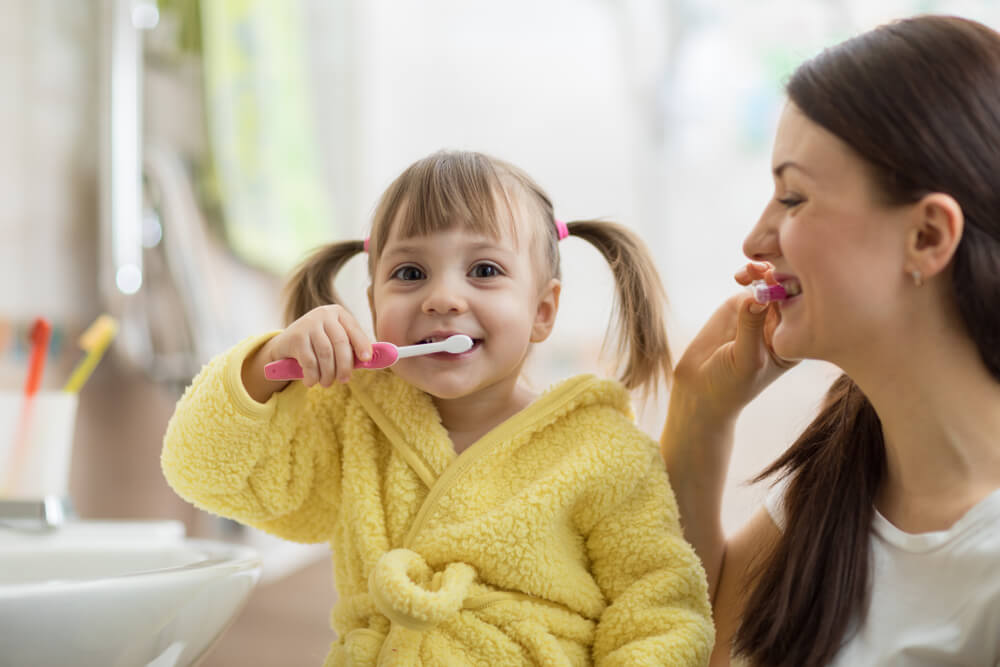 Mother and daughter brushing their teeth