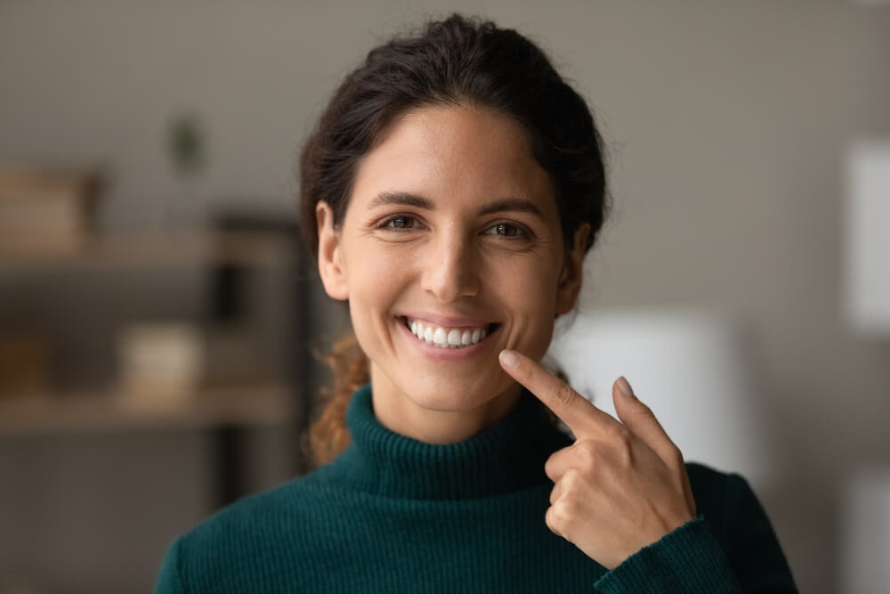 Woman pointing to her bright smile
