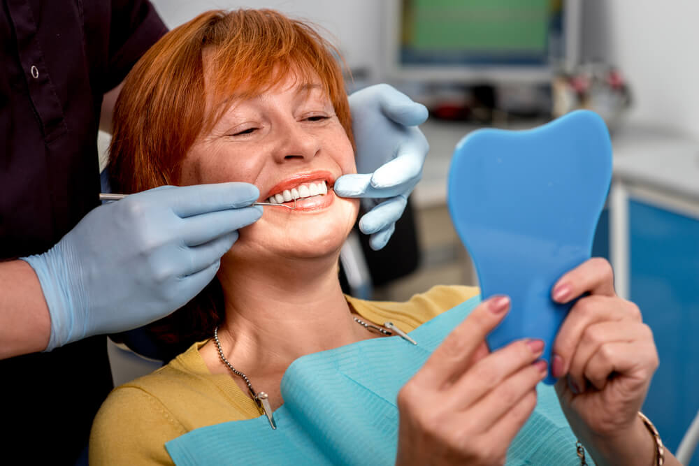 Woman looking at her smile at the dentist
